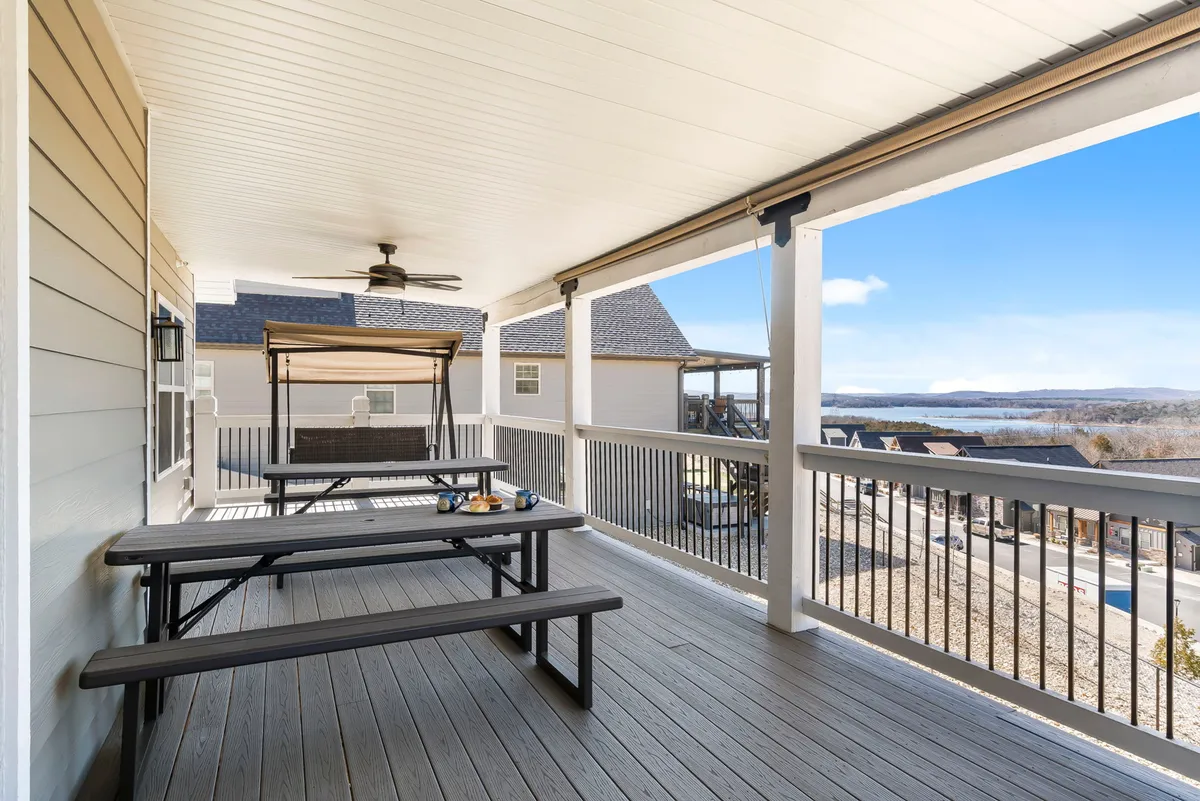A relaxed lakeside picnic area with wooden tables under an awning and a scenic view of the lake. This space is ideal for family meals, relaxation, and enjoying the outdoors with pets close by.