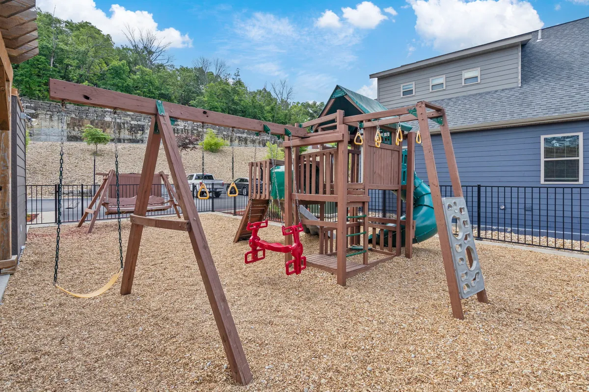 This image spotlights the community playground, complete with colorful playground equipment, swings, a safety fence, and open space for families and children to enjoy. The cheerful scene captures the joy and activity that families can experience.